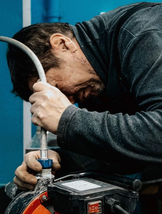 A technician concentrates on adjusting a water pump indoors.